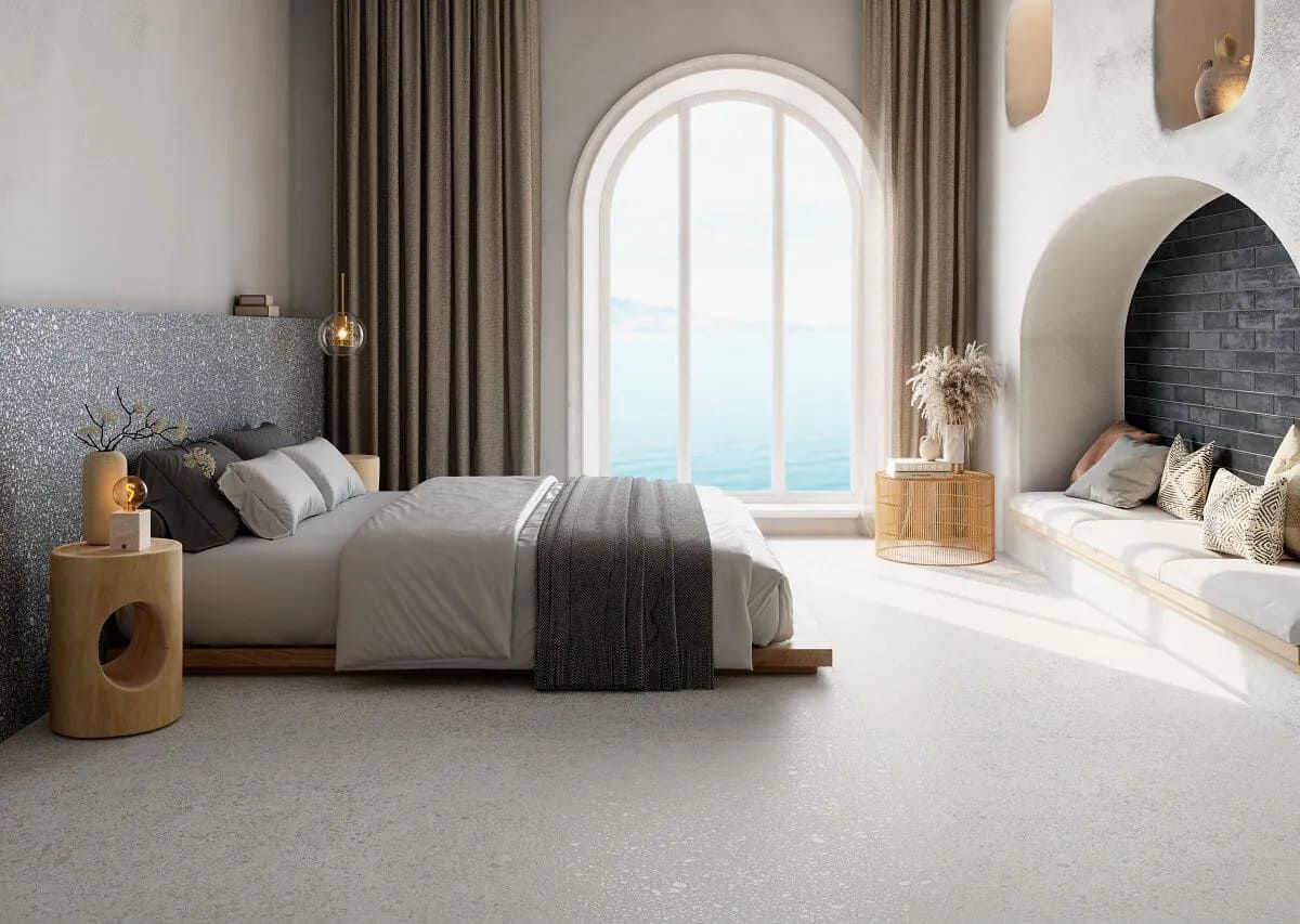 Dormitorio con cama, gran ventanal arqueado con vistas al agua y banco empotrado.