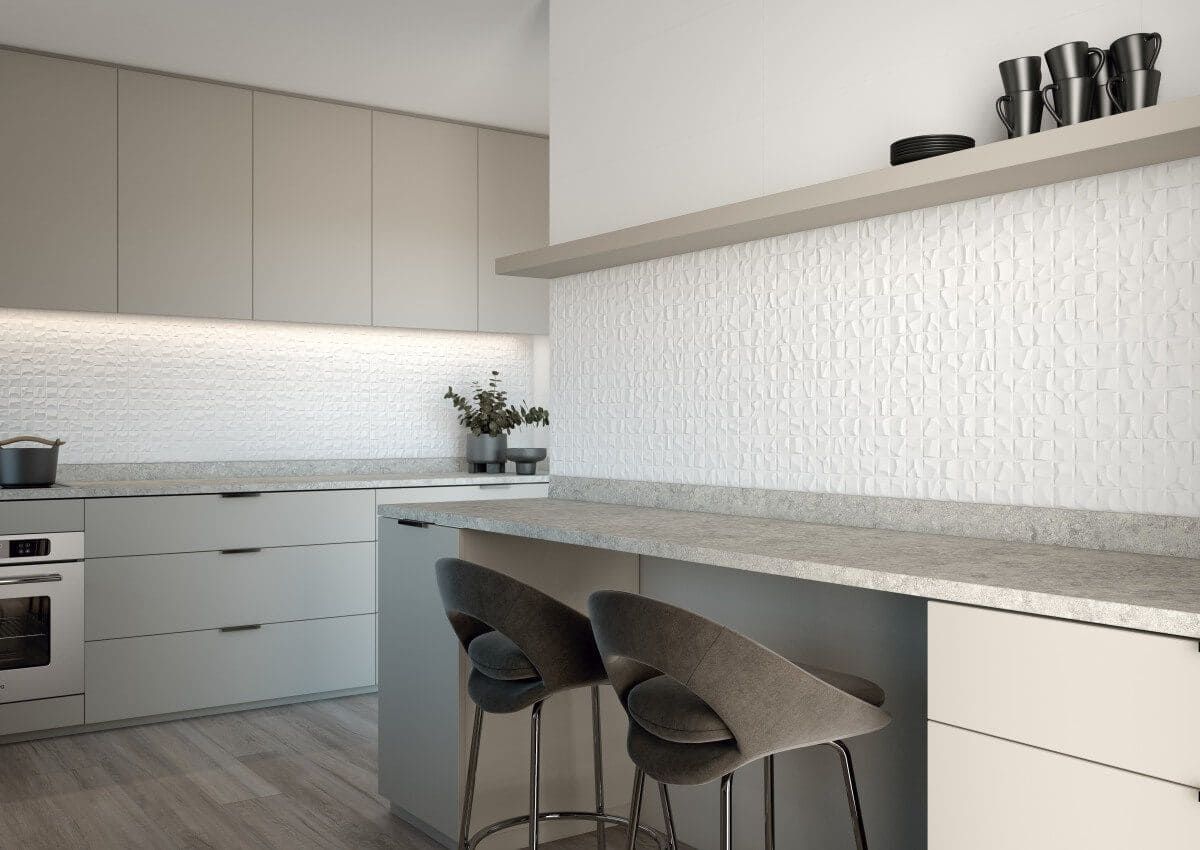 Cocina moderna con gabinetes, encimera y taburetes de bar de color gris claro; protector contra salpicaduras con textura blanca.