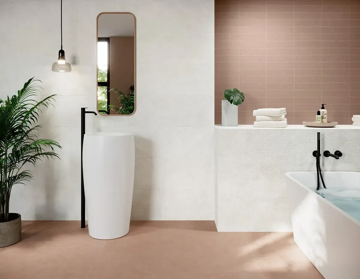 Baño moderno con lavabo de pedestal blanco, espejo y bañera; suelo color melocotón.
