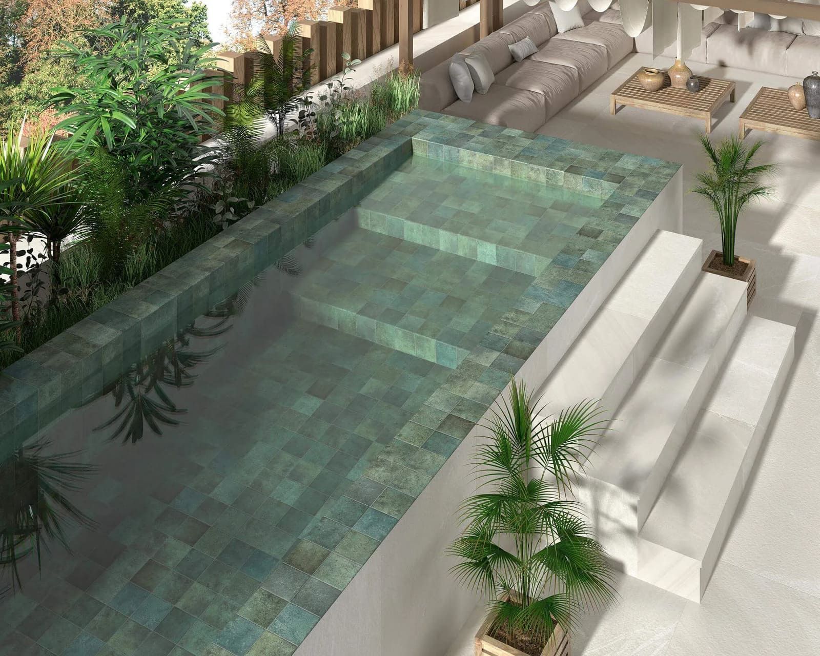 Piscina al aire libre con azulejos verdes y escalones, rodeada de plantas y muebles de patio blancos.