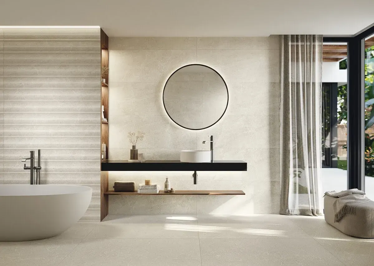 Baño moderno con tonos neutros, bañera, tocador flotante, gran espejo y abierto a la vista exterior.