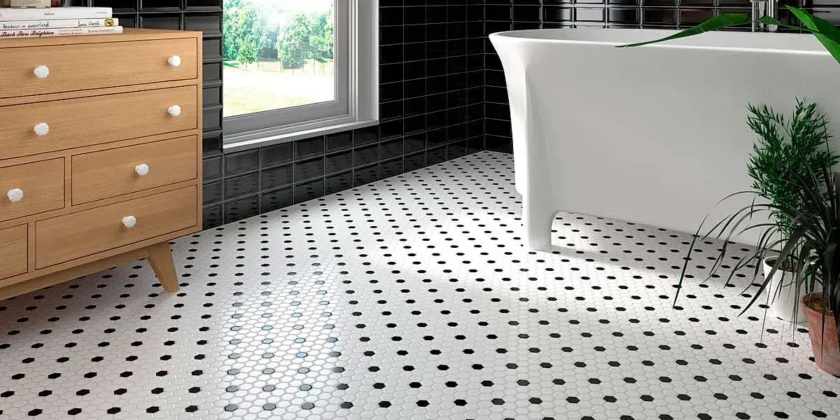 Baño con bañera blanca, cómoda de madera y suelo de baldosas. Azulejos negros forman una cuadrícula sobre fondo blanco.