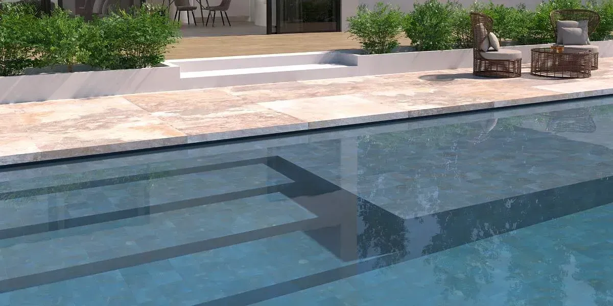 Piscina con escaleras, muebles de patio y vegetación en un entorno soleado.