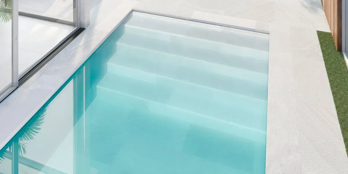 Una piscina rectangular con escalones, llena de agua azul clara.