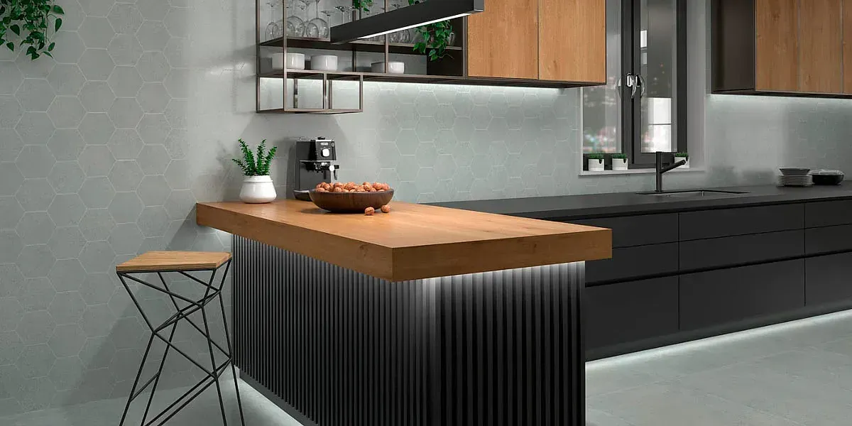 Cocina moderna con isla y gabinetes de madera, encimeras negras e iluminación decorativa.