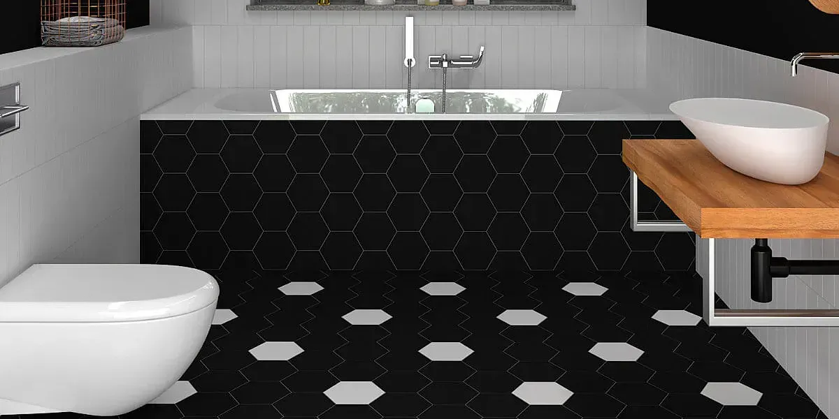Baño con azulejos hexagonales negros, inodoro blanco y lavabo de madera.