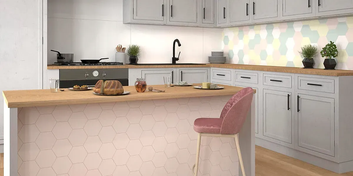 Cocina con gabinetes gris claro, encimeras de madera y un taburete de bar de terciopelo rosa. Hay un asado en la isla.