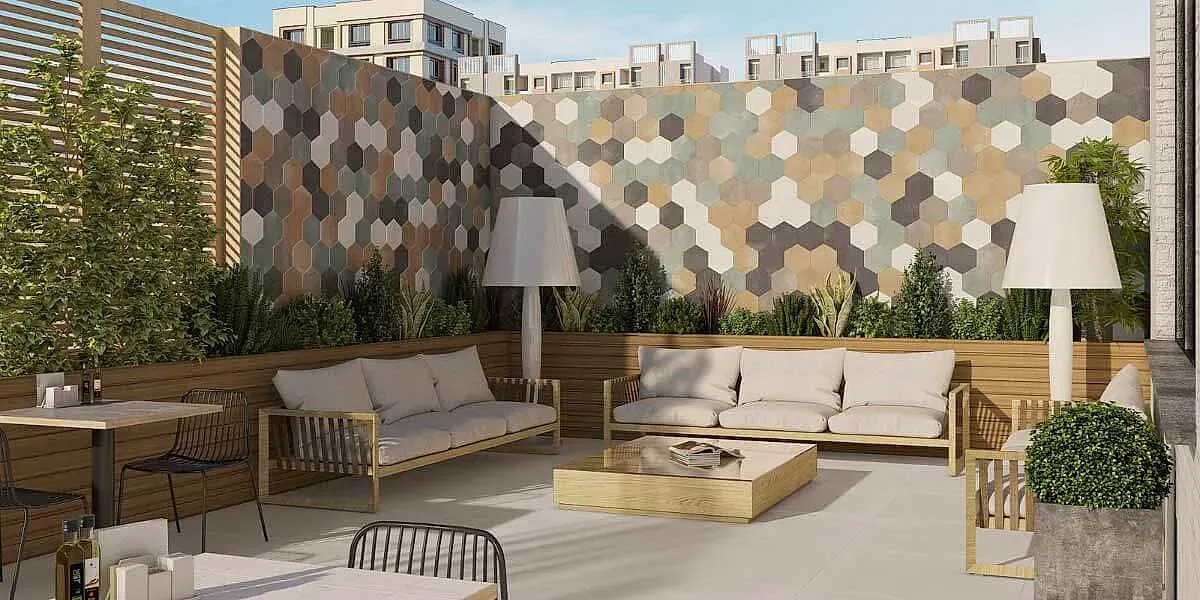 Patio al aire libre con sofás, mesa de café y pared con diseño hexagonal.