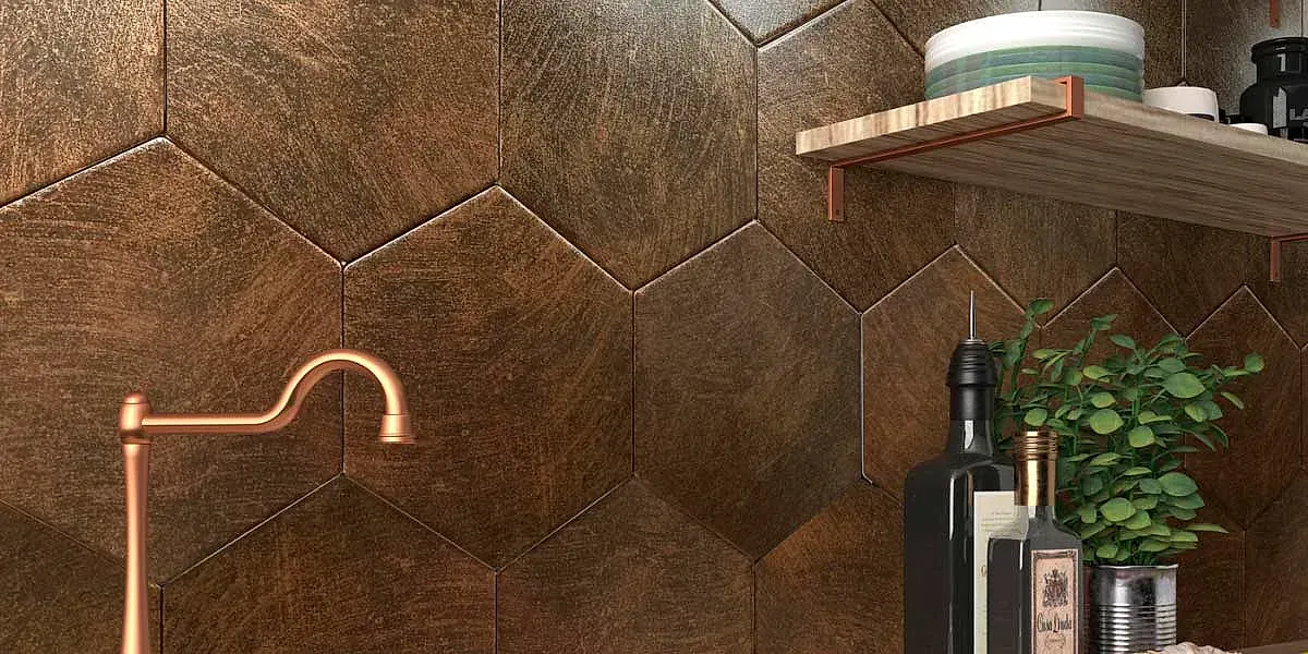 Azulejos hexagonales de color cobre en una pared detrás de un grifo de cobre, un estante y botellas con una planta.