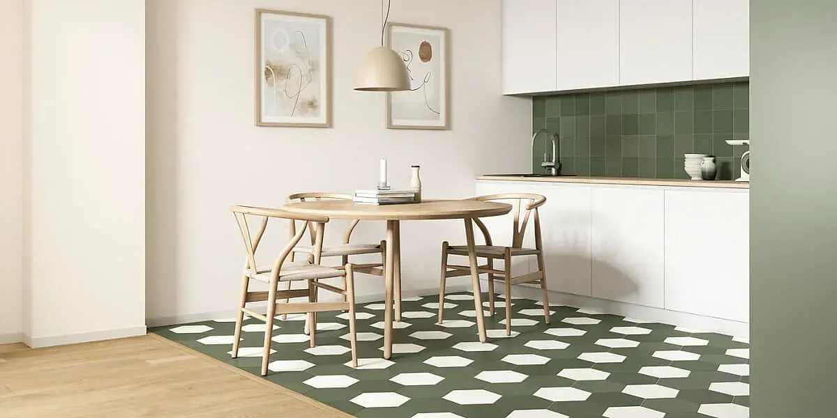 Cocina con mesa redonda de madera, sillas y suelo de baldosas con estampados verdes y blancos.