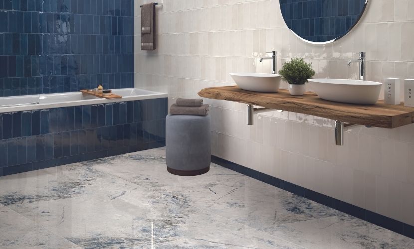 Baño con azulejos azules, paredes blancas, encimera de madera, lavabos de vasija y suelo estampado.