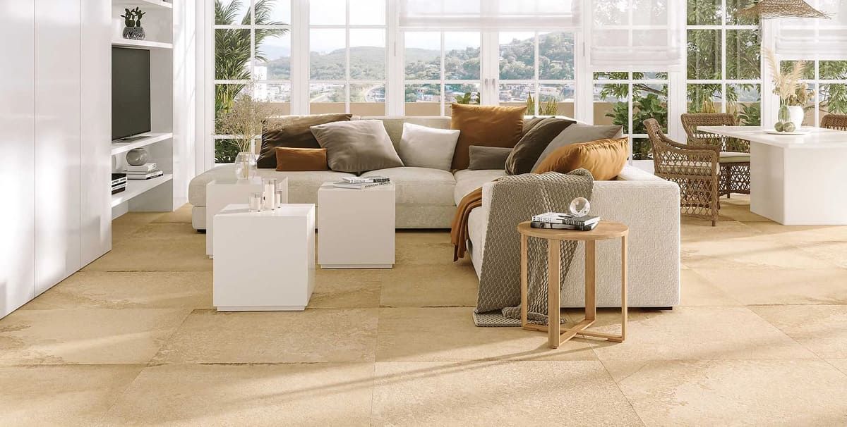 Luminosa sala de estar con sofá beige, detalles en blanco y grandes ventanales con vista panorámica.