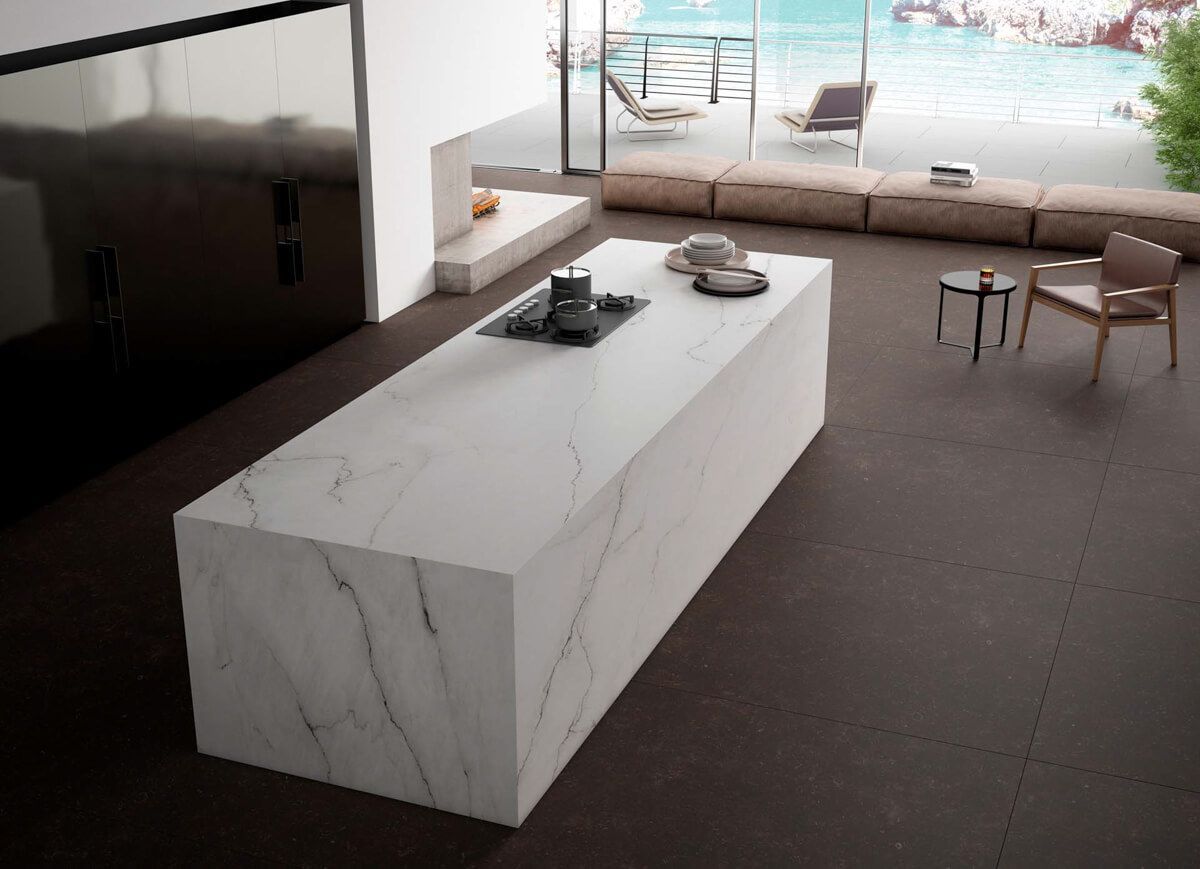 Cocina moderna con isla de mármol blanco y vista al mar.