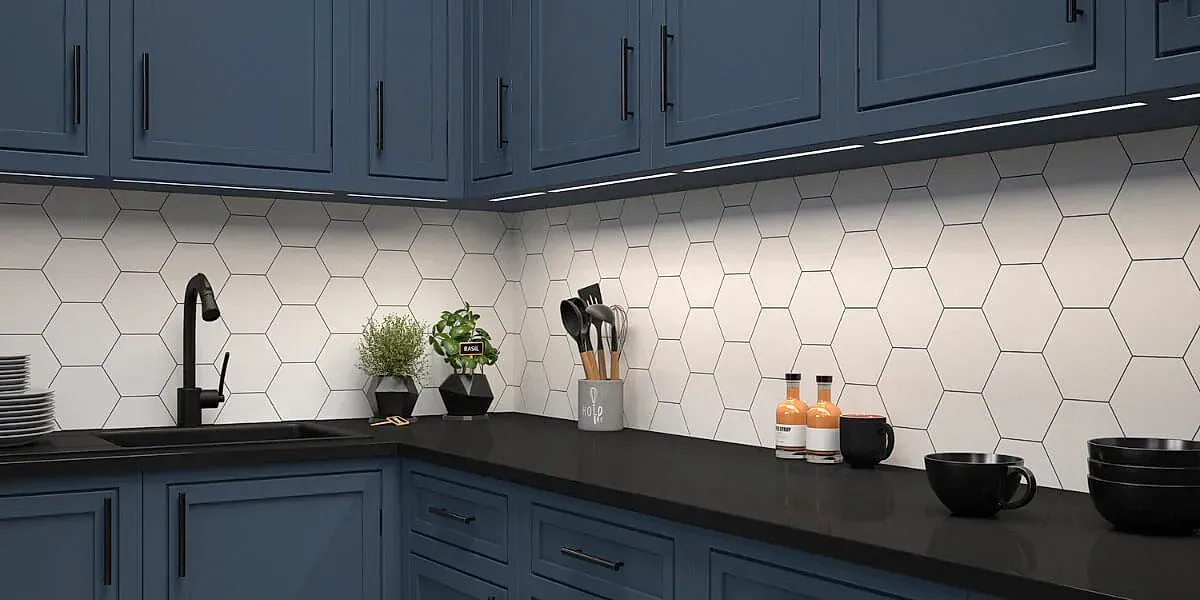 Cocina con gabinetes azules, salpicadero de azulejos hexagonales y encimeras negras.