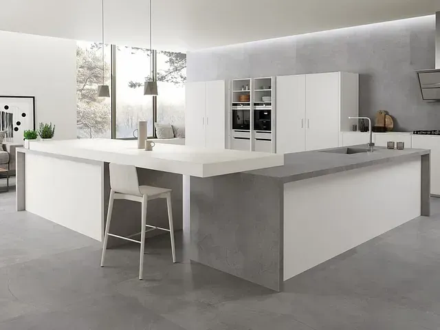 Cocina moderna en blanco y gris con gran isla y barra con asientos.