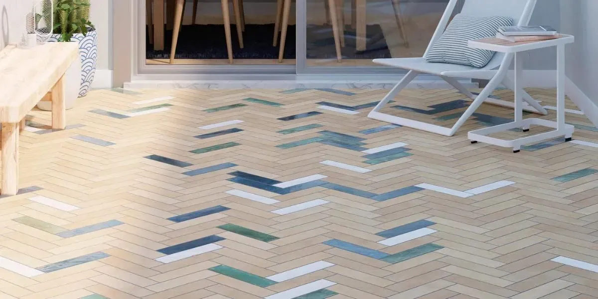 Piso de espiga con detalles en azul, verde y blanco en una habitación con una silla y una mesa blancas.