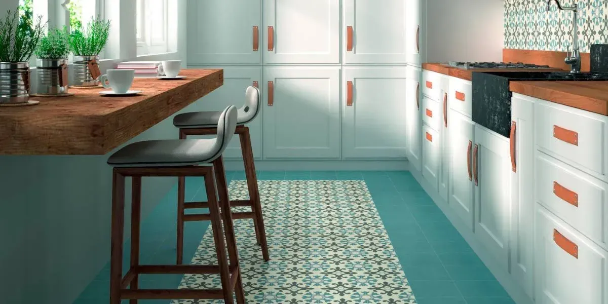 Cocina con piso verde azulado, gabinetes blancos con manijas de cobre y encimeras de madera.