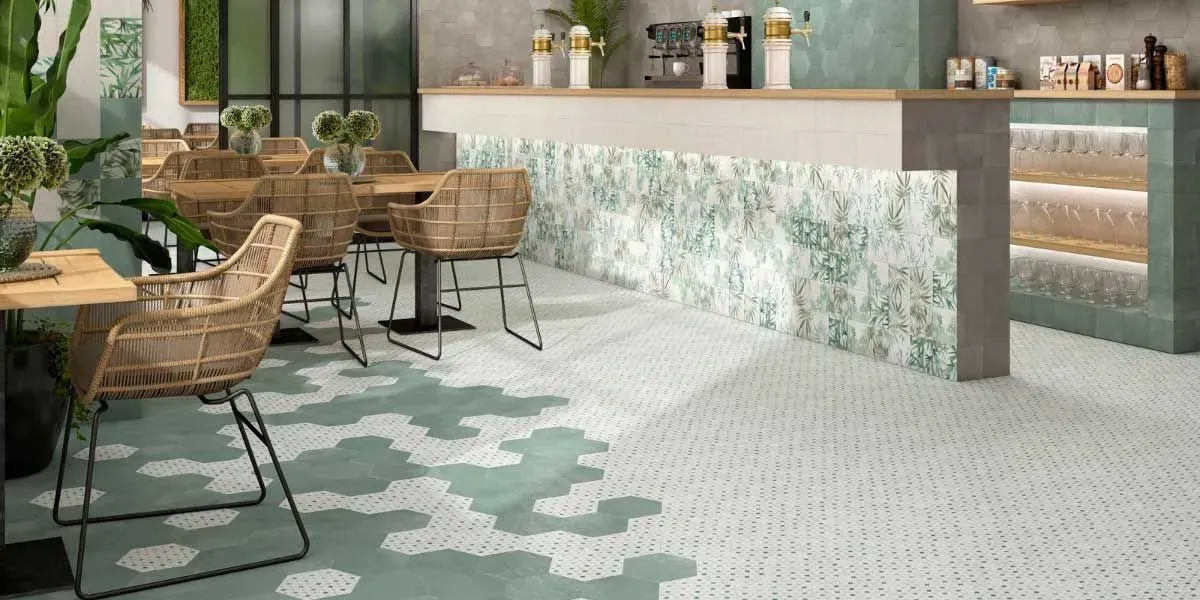 Interior de cafetería con sillas tejidas, mostrador de azulejos y suelos estampados. La paleta de colores es verde y beige.