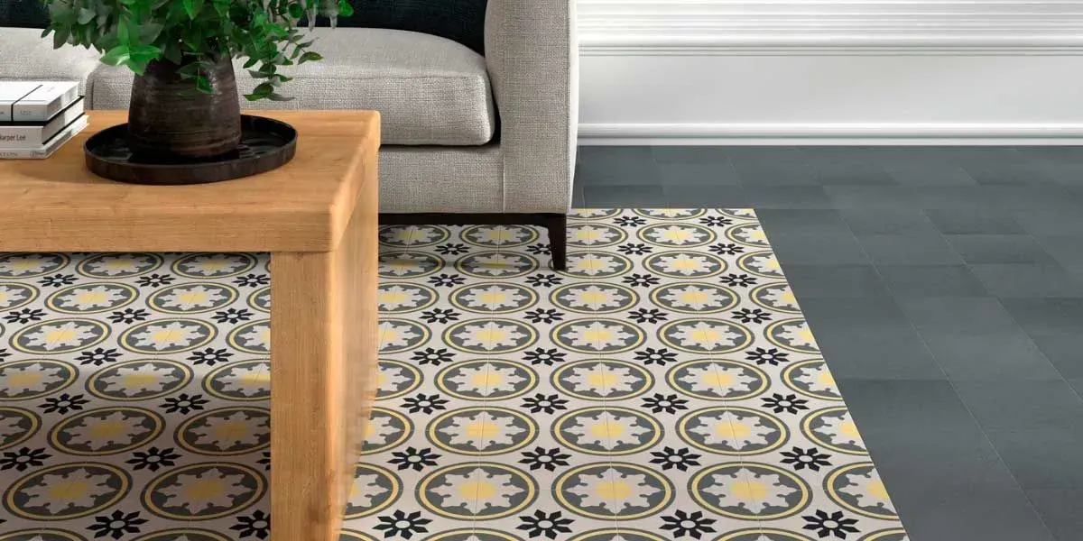 Primer plano de una sala de estar con una alfombra estampada, una mesa de café de madera y un sofá gris.