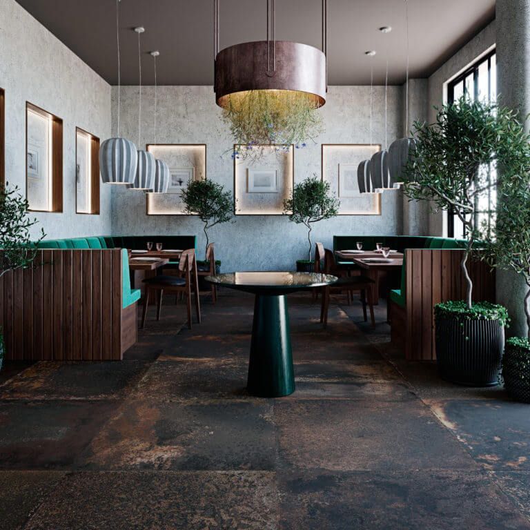 Interior de restaurante con madera oscura, detalles en verde azulado y árboles en macetas. Una lámpara de techo de bronce cuelga sobre una mesa central.