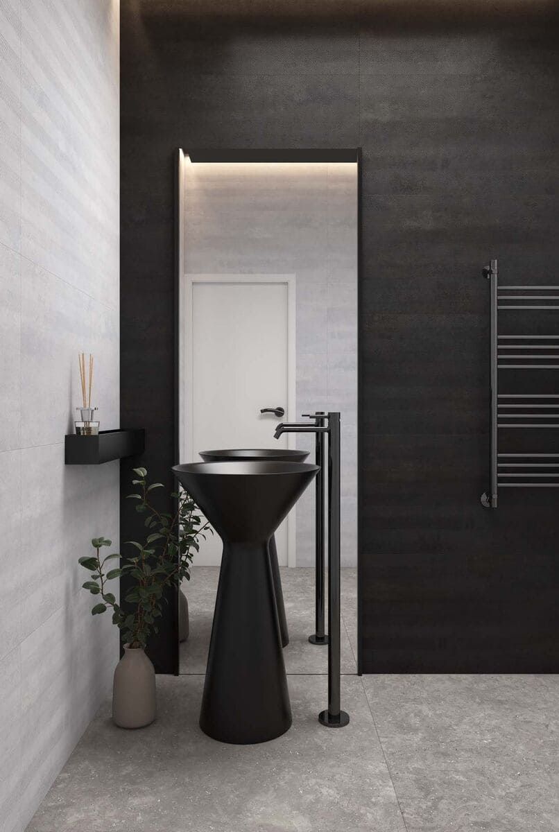 Baño moderno con lavabo de pedestal negro, pared con acento negro y piso de baldosas grises.