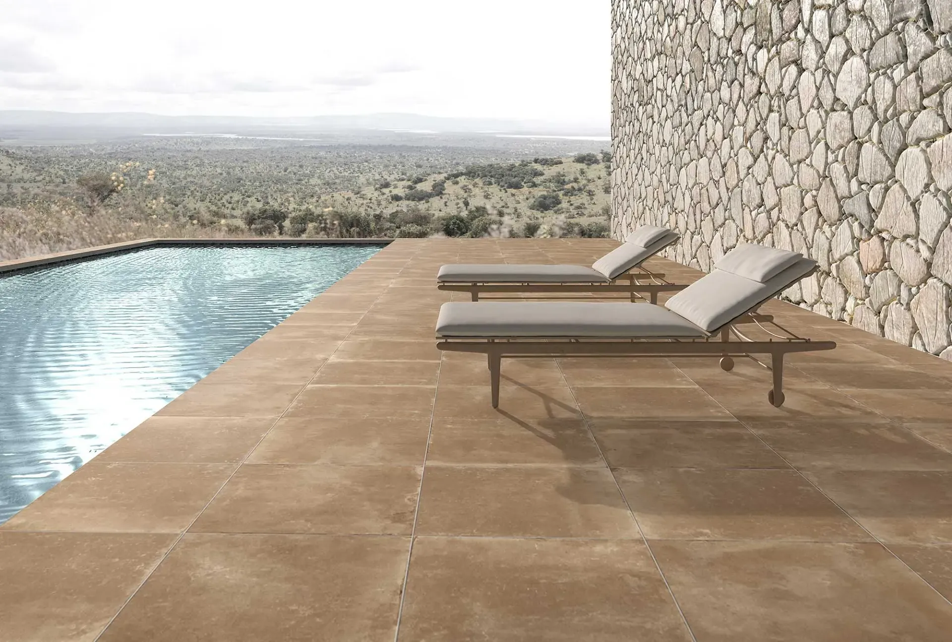 Terraza con piscina, muro de piedra y dos tumbonas con vistas a un paisaje lejano.