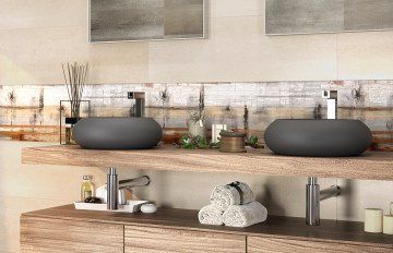 Baño con dos lavabos grises sobre un estante de madera, mueble marrón debajo, paredes beige y detalles decorativos.