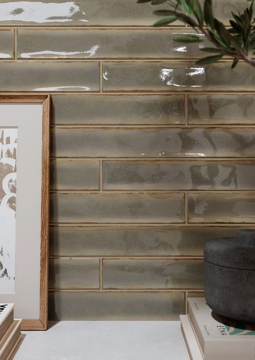 Salpicadero de azulejos grises, rectangulares, con marco, libros y una planta.