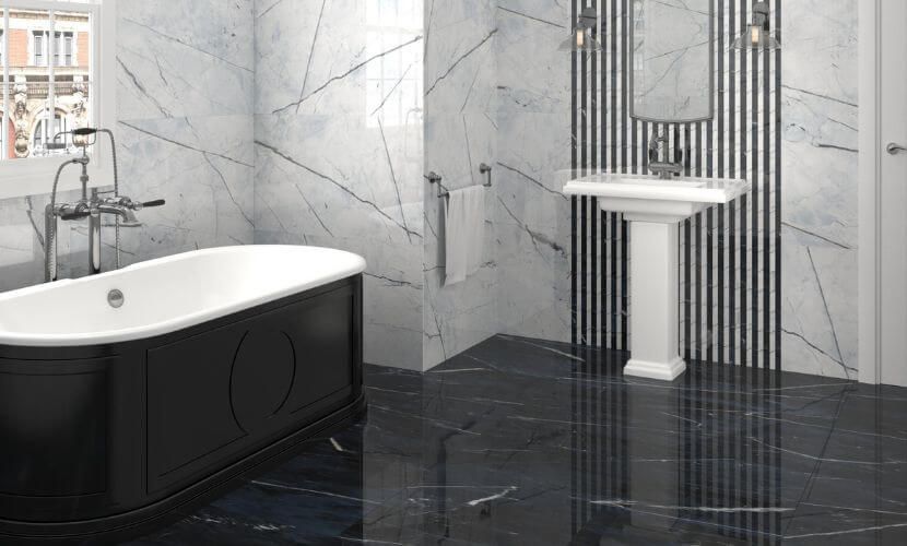 Elegante baño con azulejos de mármol blanco y negro, bañera negra y lavabo con pedestal.