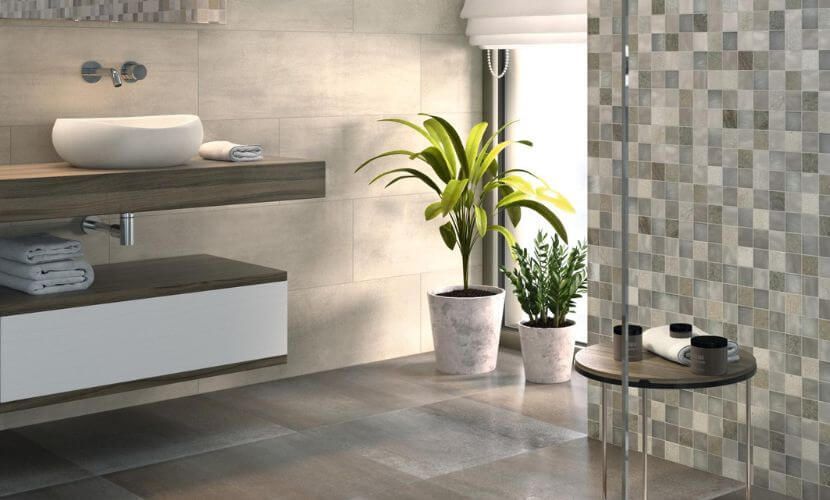 Baño moderno con tonos neutros, tocador flotante, plantas en macetas y ducha con azulejos de mosaico.