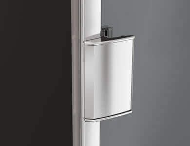 Cubo de basura de color plateado, rectangular, sujeto a un poste de color blanco, con fondo oscuro.