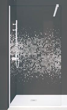 Cabina de ducha con mampara de cristal con diseño geométrico blanco. Paredes grises y grifería blanca.