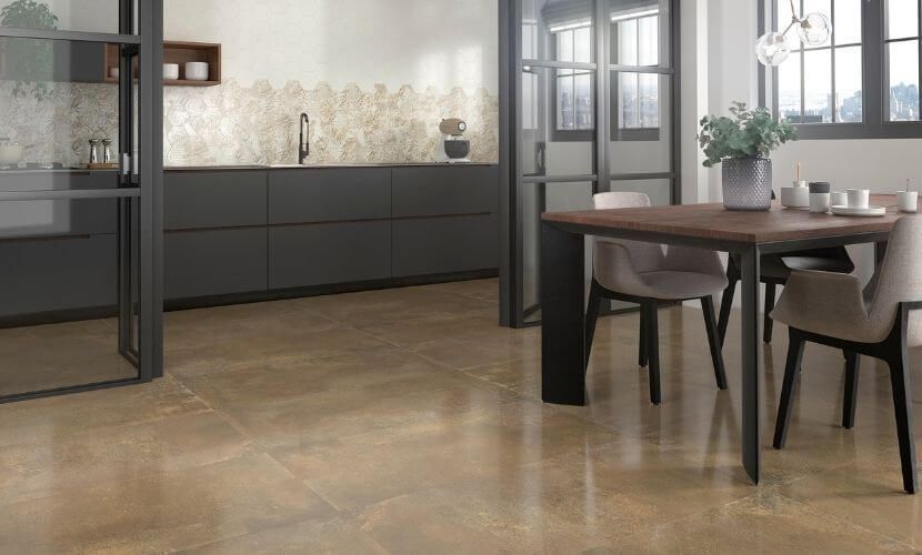 Cocina y comedor modernos con gabinetes oscuros, mesa de madera y piso beige.