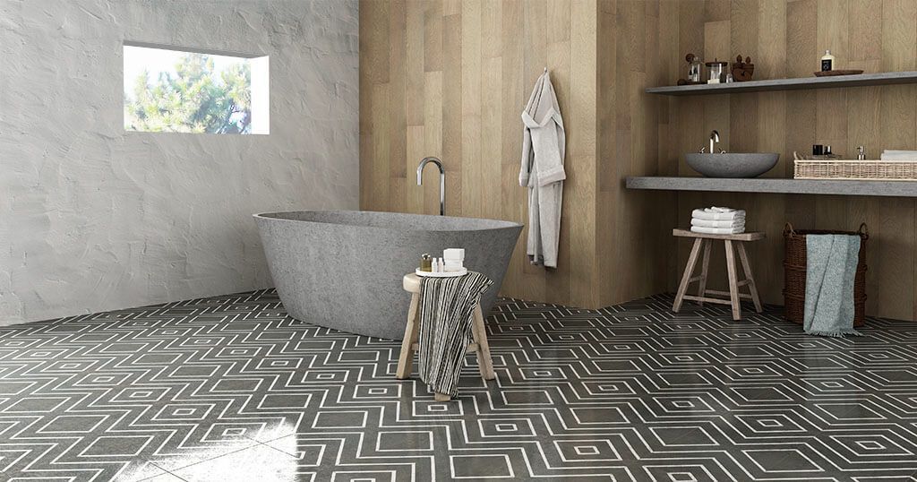 Baño con suelo oscuro estampado, pared de madera, bañera de piedra y estanterías con artículos de aseo.