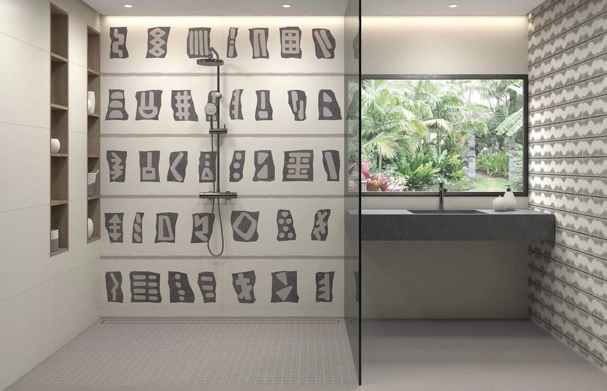 Baño moderno con ducha, paredes de azulejos estampados, puerta de vidrio y ventana grande con vista a la vegetación.