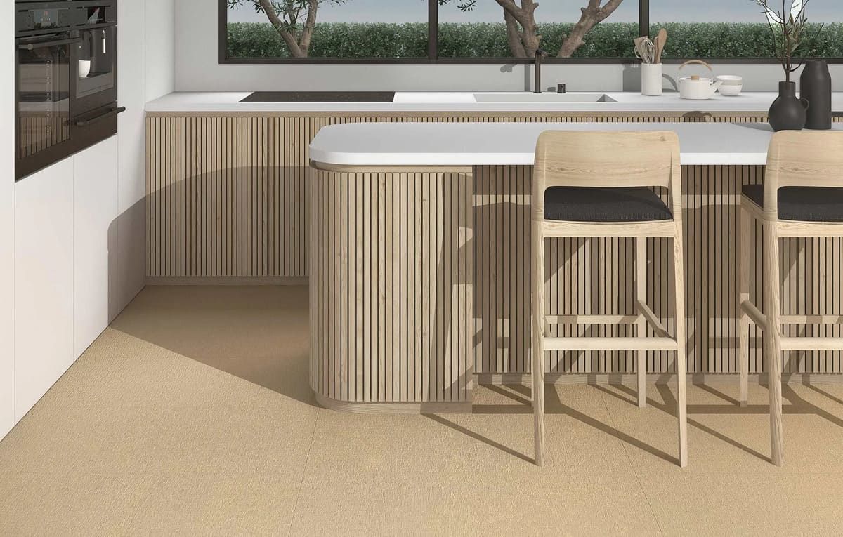 Cocina moderna con detalles en madera clara, barra con asientos y ventana grande.