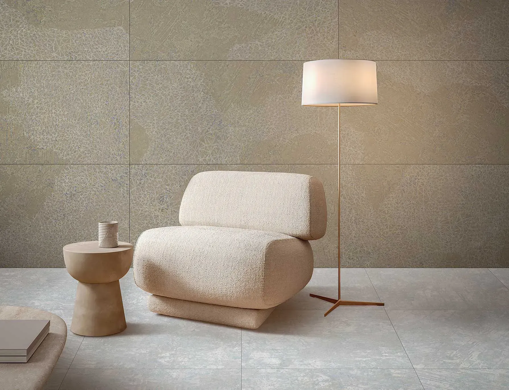 Acogedora sala de estar con pared texturizada beige, sillón, lámpara de pie y mesa auxiliar.