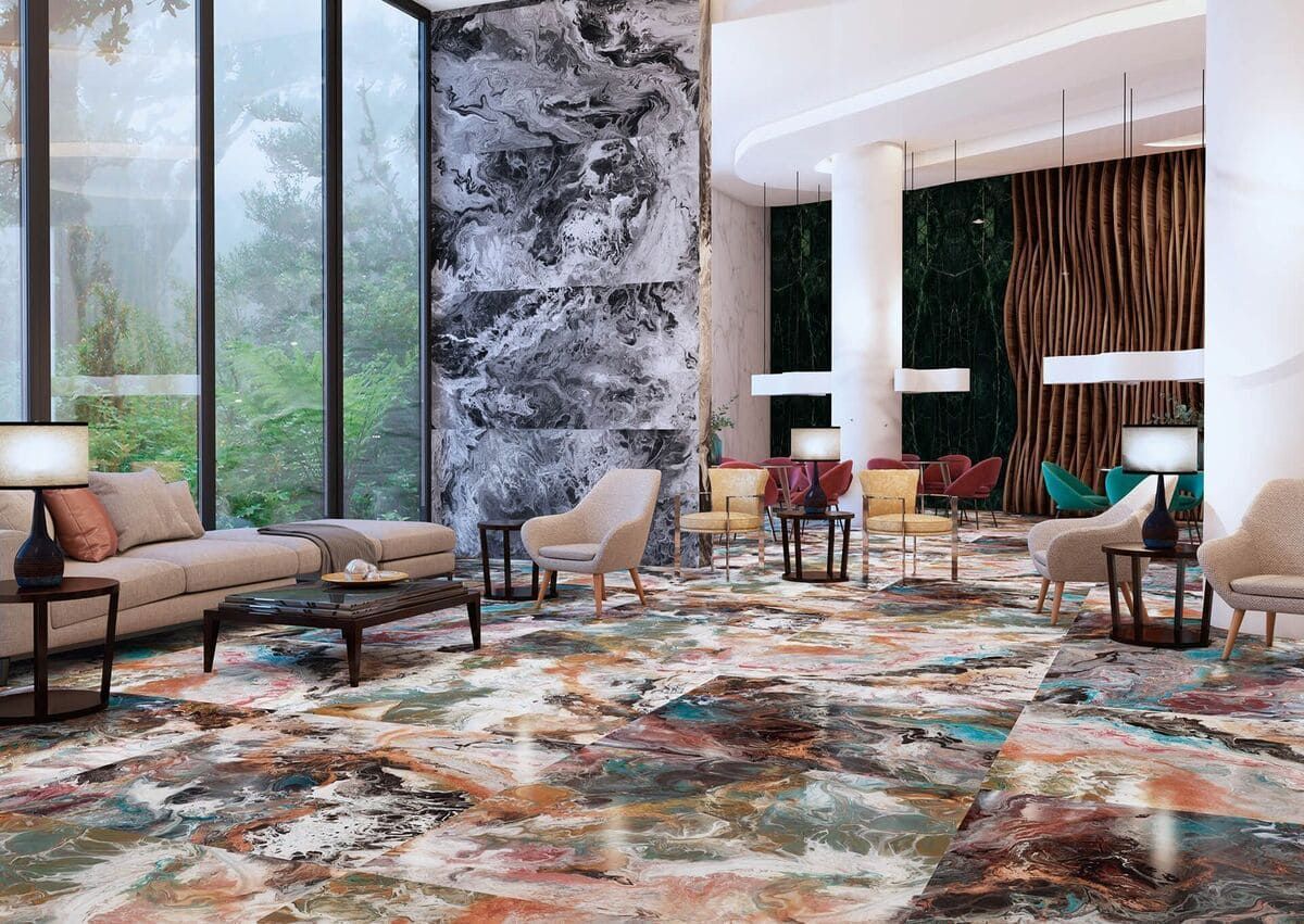 Vestíbulo con columnas de mármol, alfombra estampada, asientos y un gran ventanal con vista a la vegetación.