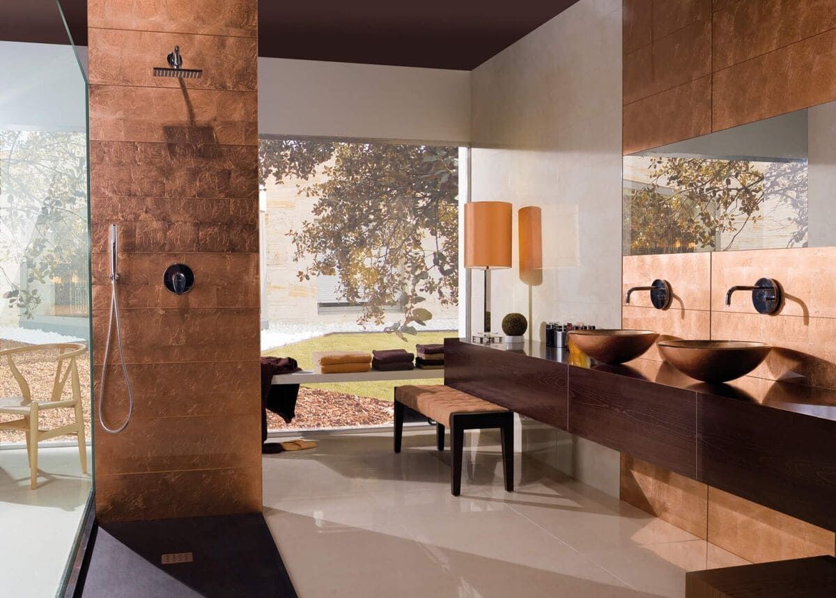 Baño moderno con paredes en tonos cobre, tocador de madera oscura, ventana grande con vista panorámica al aire libre.