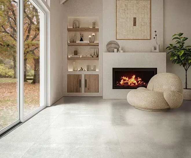 Moderna sala de estar con chimenea, estantes empotrados, gran ventanal con vista al follaje otoñal y un acogedor sillón.