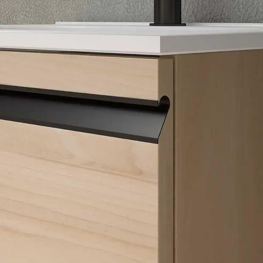 Primer plano de un mueble de baño de madera clara con tirador empotrado negro, debajo de una encimera blanca.