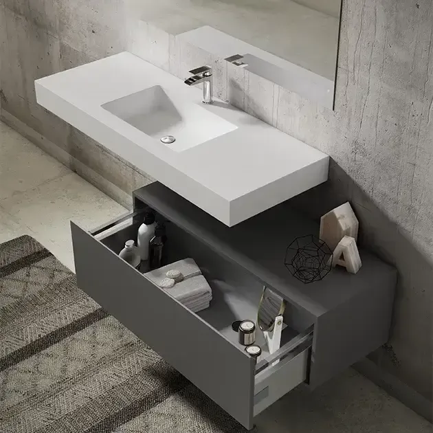 Lavabo flotante blanco y mueble con cajones gris en un baño moderno.