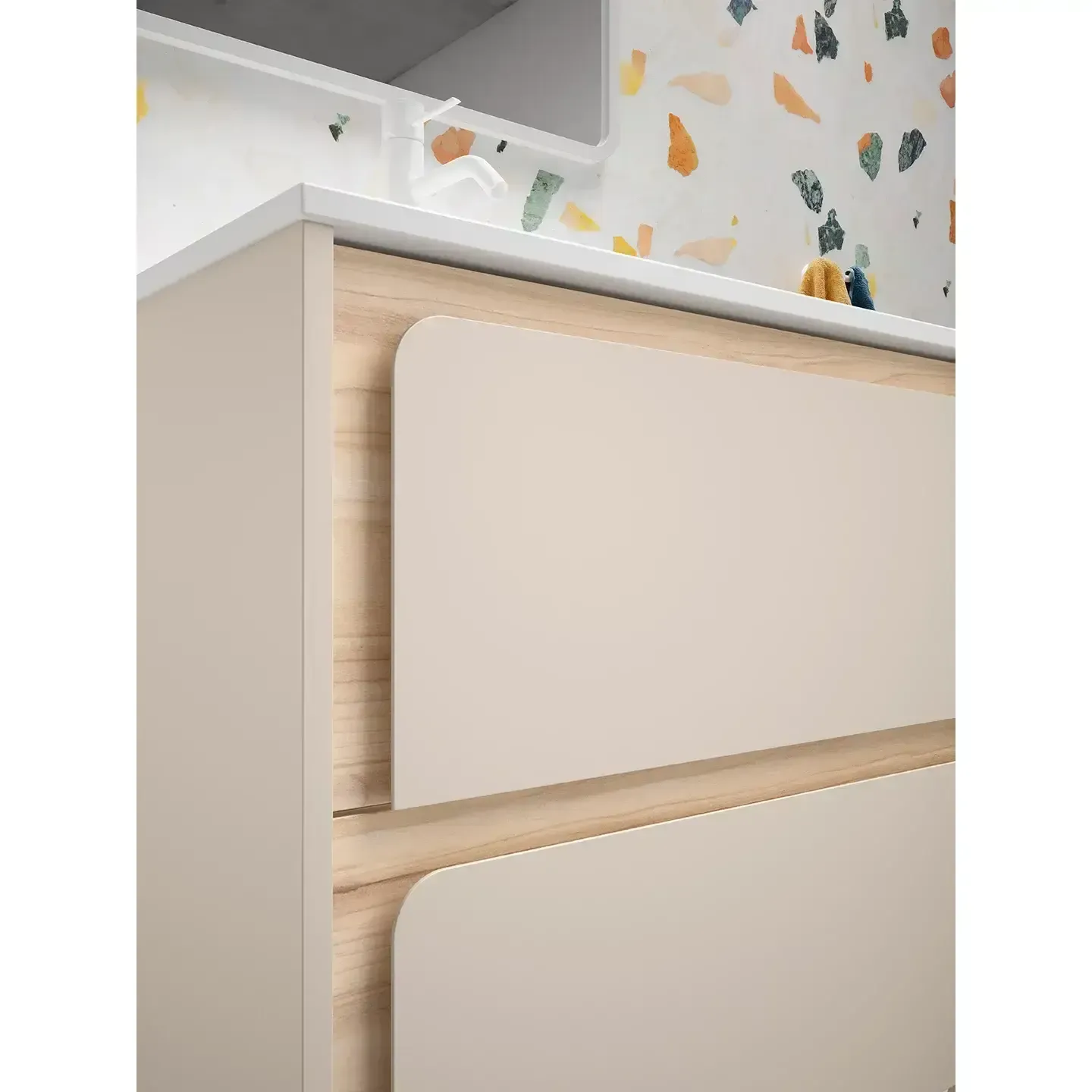 Mueble de baño beige con dos cajones y molduras de madera, sobre una pared colorida.