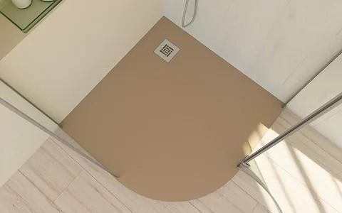 Ducha de esquina de color tostado con frente curvo, paredes blancas y desagüe.