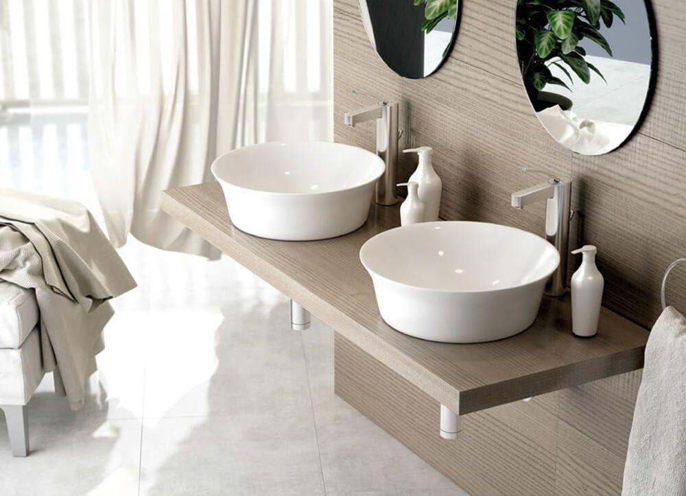 Lavabo doble de baño sobre encimera de madera, lavabos blancos, grifería cromada, paredes beige, espejos.