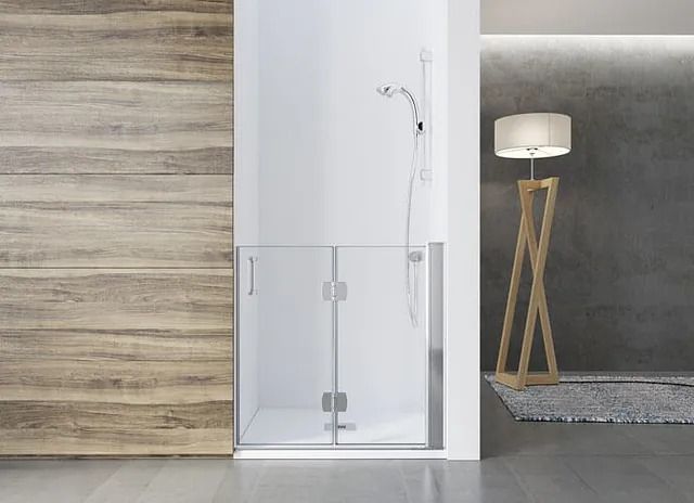 Mampara de ducha de cristal con paredes blancas, puerta de madera y lámpara de pie.