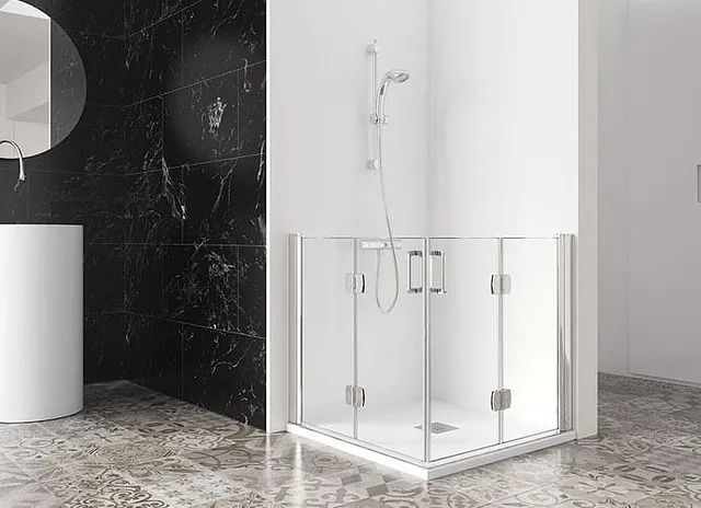 Baño moderno con ducha de esquina cerrada por puertas de cristal; accesorios blancos contra una pared con apariencia de mármol.