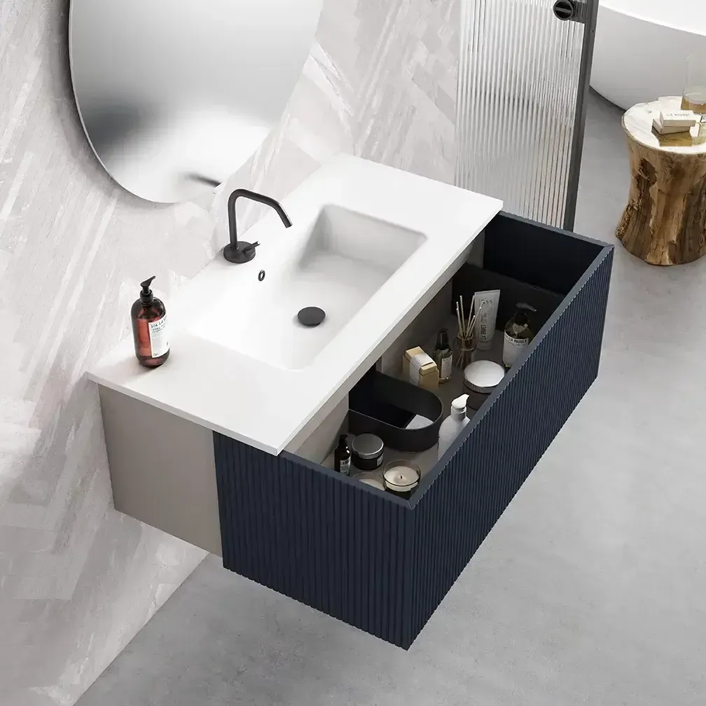 Moderno tocador de baño azul con lavabo, espejo y cajón abierto para artículos de aseo. Tonos grises y blancos.