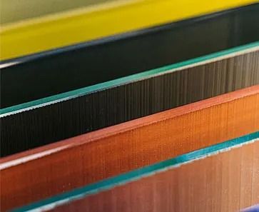 Primer plano de láminas de vidrio de colores, en capas, cada una de un color diferente, apiladas.