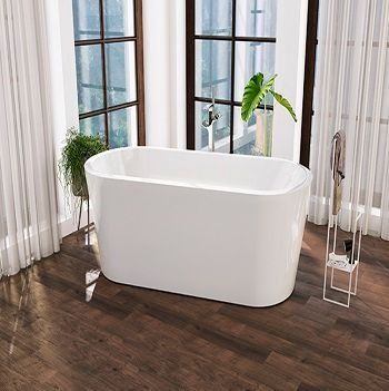 Bañera blanca en un baño moderno con suelo de madera oscura y grandes ventanales.